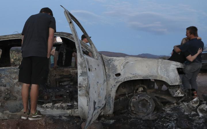 Members of the Lebaron family look at the burned car where part of the nine murdered members of the family were killed and burned during an ambush in Bavispe Sonora mountains Mexico