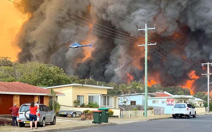 Flames from an out of control bushfire seen from a nearby residential area in Harrington some 335km northeast of Sydney