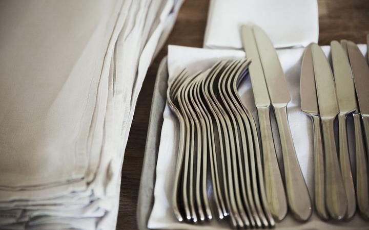 [England] High angle close up of napkins and silver forks and knives on a table in a restaurant. (Photo by Mint Images / Mint Images / Mint Images via AFP)