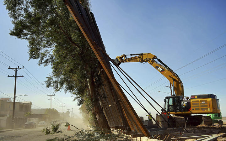 A construction crew works on a fallen section of the US-Mexico border wall as seen from Mexicali Baja California state Mexico