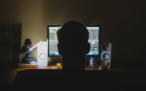 man in dark room in front of computer screen, computer generic