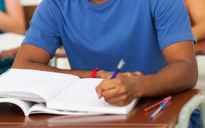 A young man in a classroom, writing, in a file photo to illustrate foreign students. 