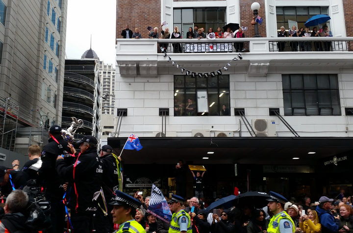 Fans hang off the balcony to catch a glimpse of the America's Cup