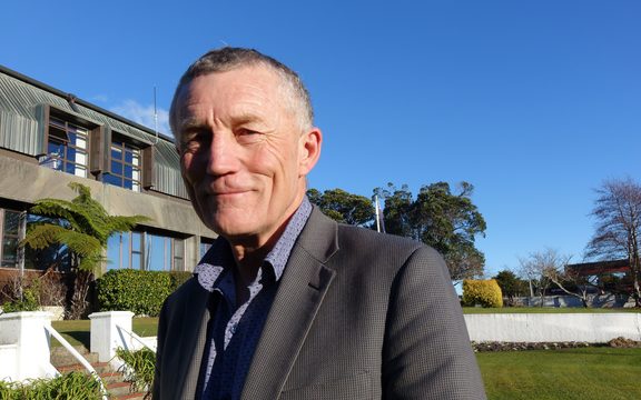 Man stands outside offices under blue sky