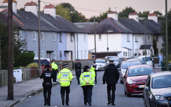 Police stand guard during the raid in Sunbury, Surrey near London.