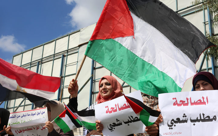 Palestinians wave flags during a support rally for Palestinian reconciliation