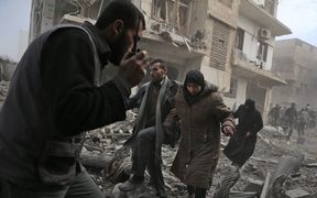 A member of the Syrian civil defence speaks on a wireless transmitter as other civilians flee from an area hit by a reported regime air strike in the rebel-held town of Saqba, in the besieged Eastern Ghouta region on the outskirts of the capital Damascus, on February 20, 2018. 