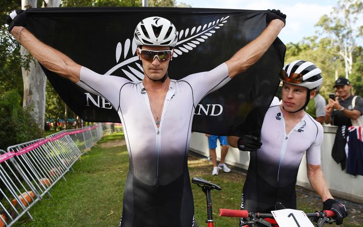 New Zealand's Samuel Gaze celebrates winning the mountain bike race as team mate Anton Cooper looks on.