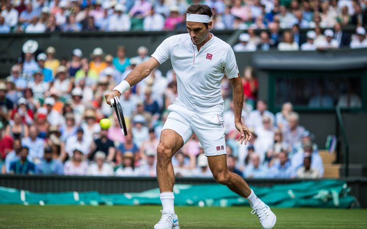 Roger Federer leans into his trademark backhand at Wimbledon.