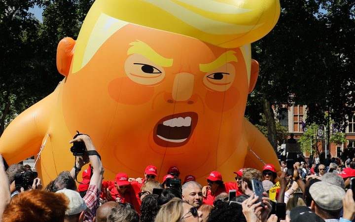 Activists inflate a giant balloon depicting US President Donald Trump as an orange baby during a demonstration against Trump's visit to the UK in Parliament Square in London.

