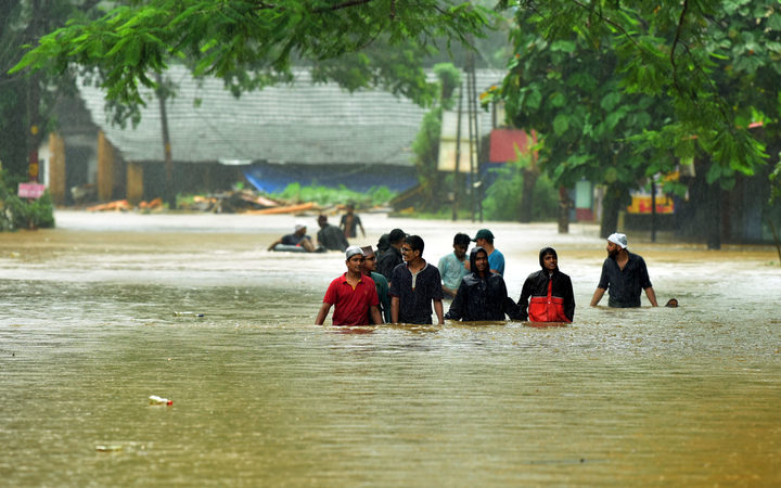 People crossing the flooded road at Engapuzha in Kozhikode