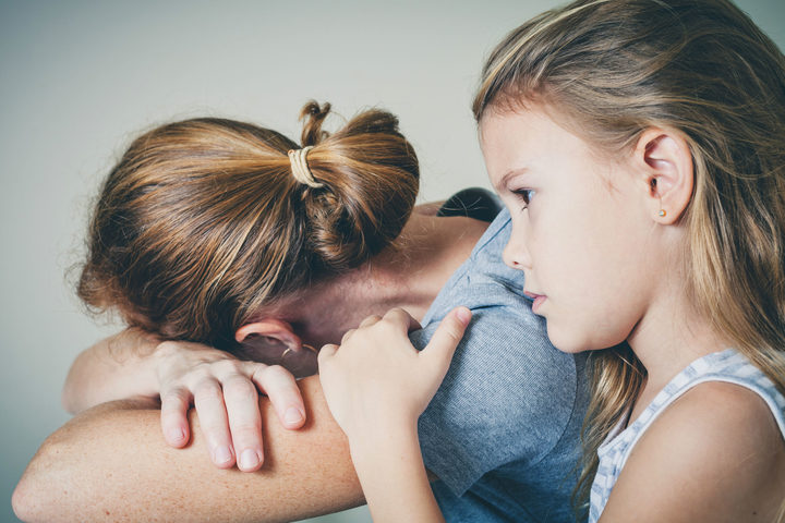 49451378 A photo of a sad daughter hugging her mother at home. conveys the sense that the family is in sorrow.