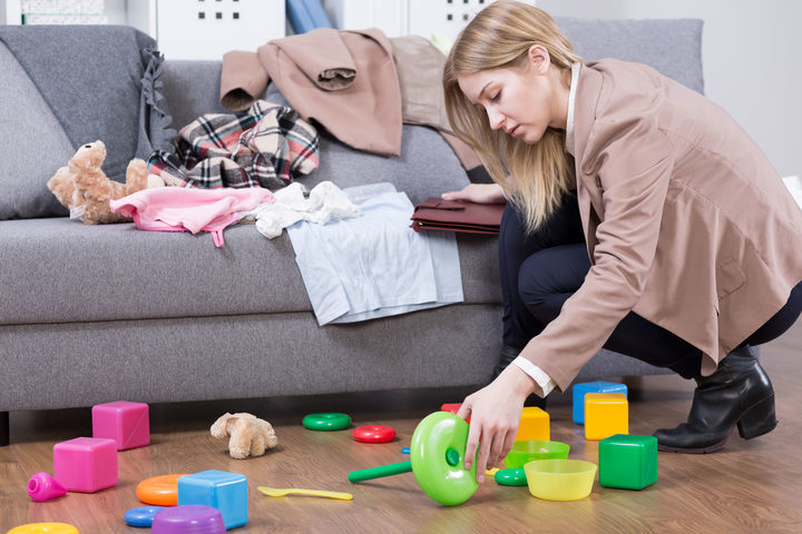 Young mother cleaning her kid's toys at home. Woman tired after work