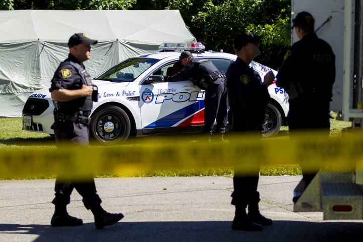Members of the Ontario Provincial Police confer with colleagues after a third day of searching for human remains in a ravine behind a home on Mallory Crescent in Toronto, Ontario, July 6, 2018 in connection with the investigation of accused serial killer Bruce McArthur. 