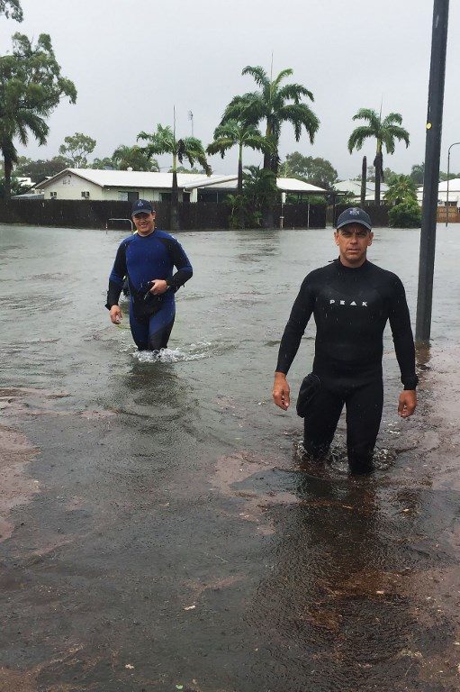 A handout picture provided by Queensland Police Service, taken on February 2, 2019 and release on February 3 shows two police officers wading in flood waters in Townsville. - 