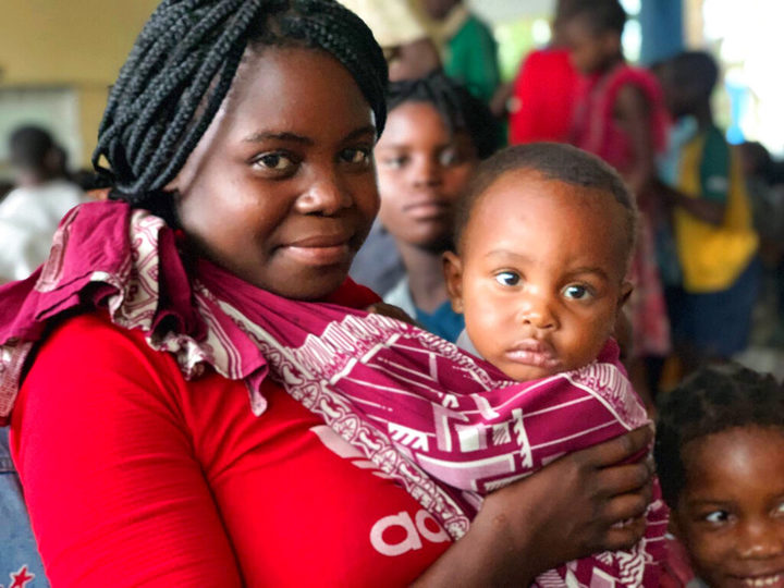 In this photo provided by World Food Programme (WFP) , Lina and her baby smile for the media as they wait to receive food in Beira, Mozambique. Lina had to flee her home with her baby when Cyclone Idai hit l
