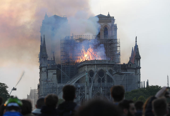 People watch as flames and smoke rise from Notre-Dame cathedral.