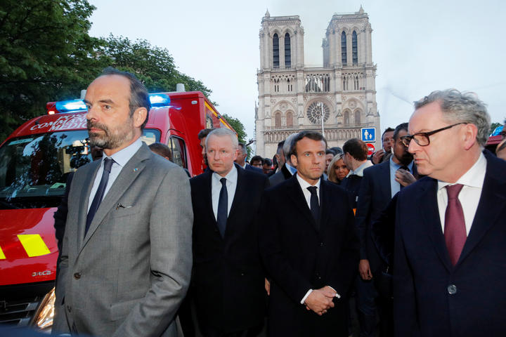 French Prime Minister Edouard Philippe, left, President Emmanuel Macron, centre, near the entrance of the Notre-Dame de Paris Cathedral , as flames engulf its roof.