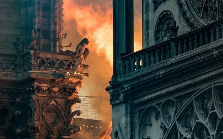 Flames and smoke billow around the gargoyles decorating the roof and sides of the Notre Dame Cathedral in Paris