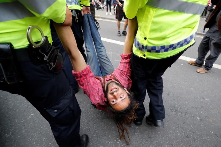 Police officers remove a climate change activist at Oxford Circus on the third day of its blockade by environmental protest group Extinction Rebellion. 