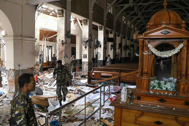  Sri Lankan security personnel walk past dead bodies covered with blankets amid blast debris at St. Anthony's Shrine following an explosion in the church in Kochchikade in Colombo on April 21, 2019. 
