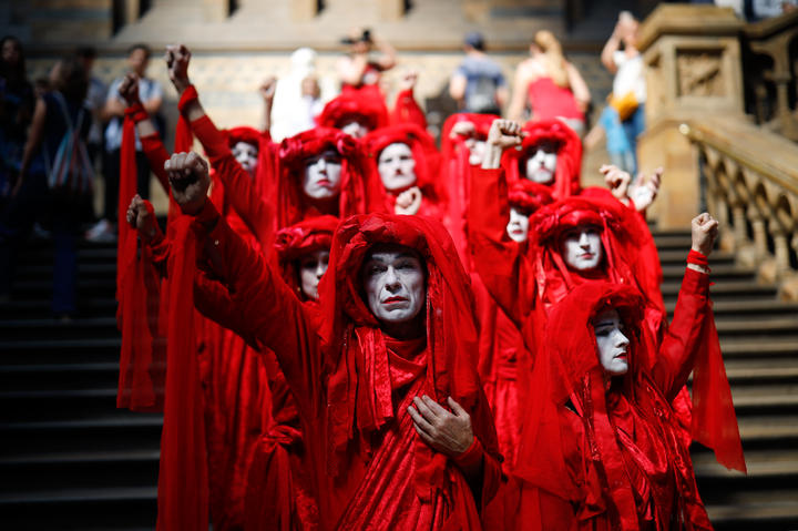 Extinction Rebellion climate change activists in red costume attend a mass "die in" in the main hall of the Natural History Museum in London.