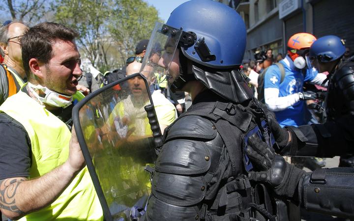A demonstrator in a yellow vest, left, speaks with a French anti-riot police officer during a yellow vest demonstration in Paris, Saturday, April 20, 2019.