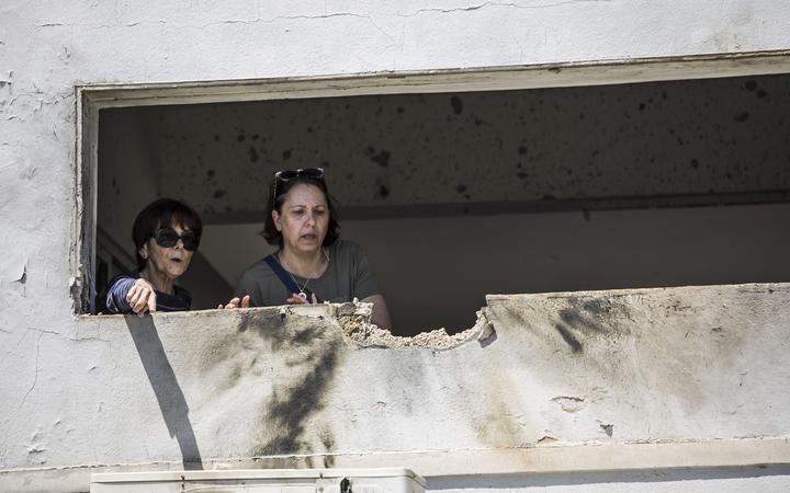 Women look at the damage caused by a rocket fired from Gaza that hit a house in a moshav in Israel near the border with Gaza, Saturday, May 4, 2019. 