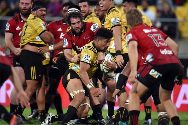 Kane Le'aupepe looks on in the background on his Super Rugby debut as Ardie Savea is tackled by Sam Whitelock.