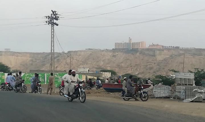 Pakistani residents watch from a road the five-star Pearl Continental hotel, located on a hill (top back) in the southwestern Pakistani city of Gwadar, on May 11, 2019.