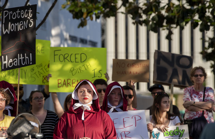 Margeaux Hartline, dressed as a handmaid, protests against the ban. 