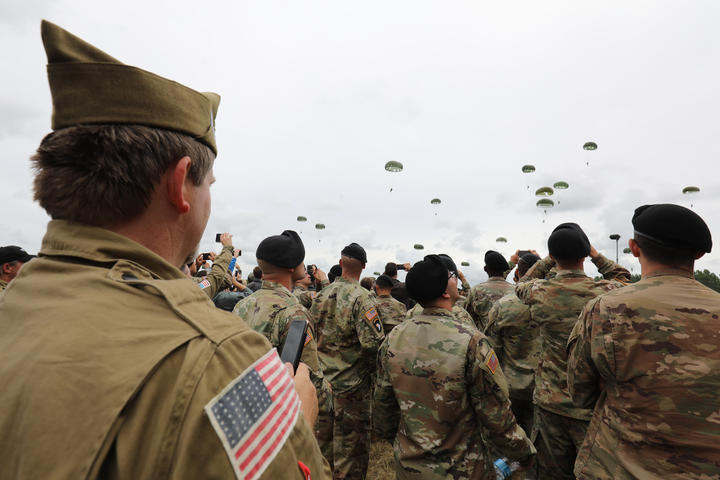 US soldiers and members of the public watch paratroopers taking part in a parachute drop over Carentan, Normandy, north-western France, on 5 June 2019, as part of D-Day commemorations marking the 75th anniversary of the World War II Allied landings in Normandy. 