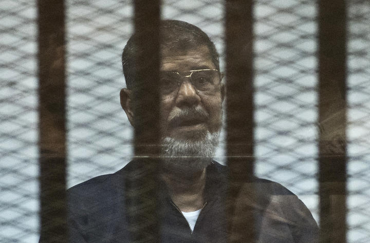 Mohamed Morsi stands behind the bars during his trial in Cairo in 2015.