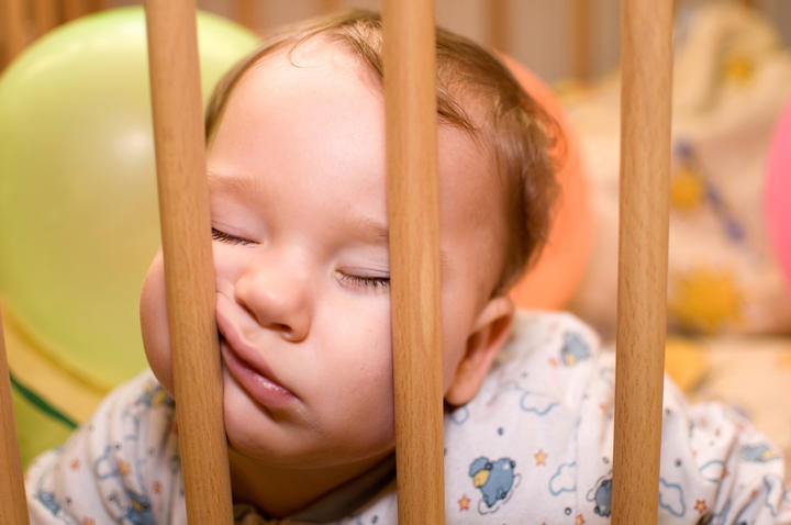 Baby sleeps with funny face in the playpen