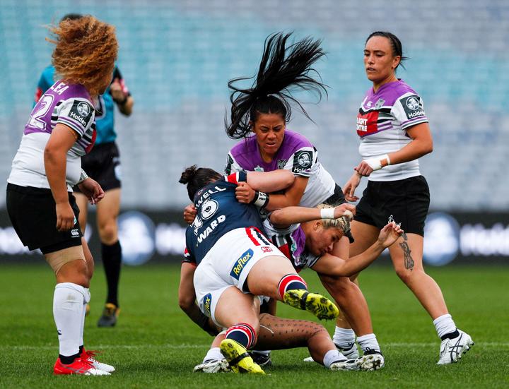 Louisa Gago (c) helps execute a tackle during the Warriors NRL Women's Premiership match against the Sydney Roosters.

