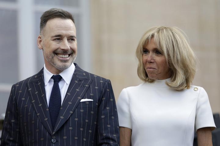 French president's wife Brigitte Macron (R) and  David Furnish, the husband of British singer-songwriter Elton John stand in  the courtyard of the Elysee Palace in Paris, on June 21, 2019, 