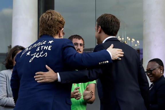French President Emmanuel Macron (R) and British singer-songwriter Elton John embrace as they address a crowd crowd in the courtyard of the Elysee Palace in Paris, on June 21, 2019, 