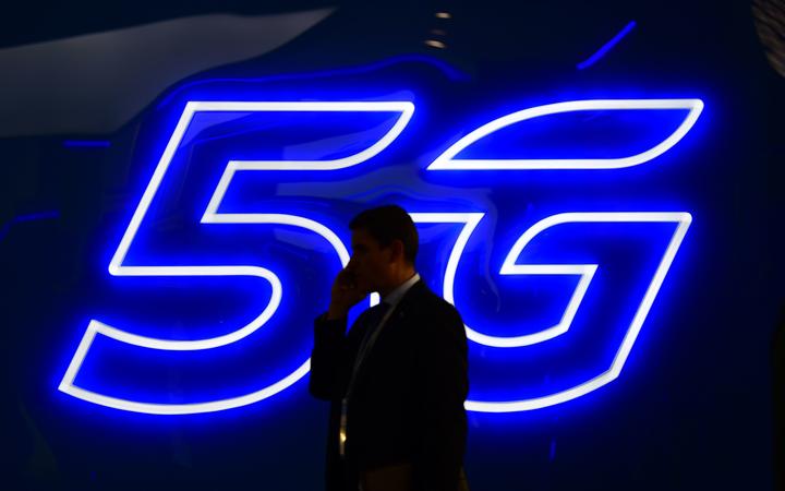 A man speaks on the phone next to a 5G hotspot sign displayed at the Mobile World Congress in Barcelona in February.