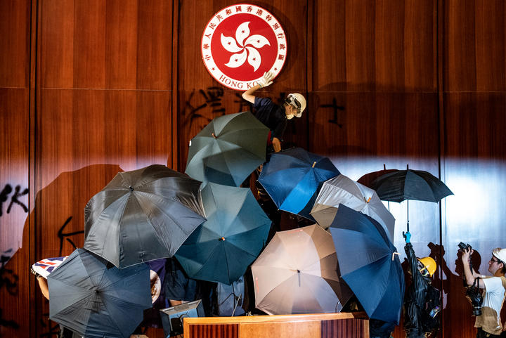 A protester defaces the Hong Kong emblem after protesters broke into the government headquarters in Hong Kong on 1 July 2019.