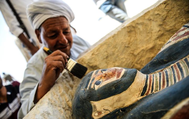 A man brushes off dust from a sarcophagus, 300 meters south of King Amenemhat IIs pyramid at Dahshur necropolis, exposed near the Bent Pyramid, about 40km  south of Cairo, during an inaugural ceremony of the pyramid and its satellites, on July 13, 2019. 