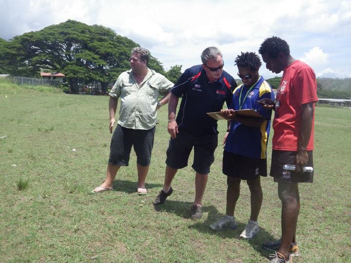 Scott Reid (L) on the job with fellow AFL staff in PNG back in 2013.
