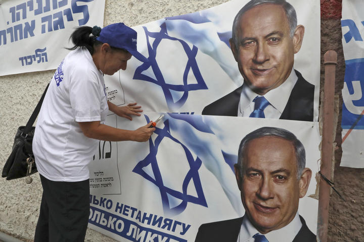 A woman places electoral banners for the Likud party showing Israeli Prime Minister Benjamin Netanyahu, in the southern Israeli city of Beersheva on 15 September 2019. 