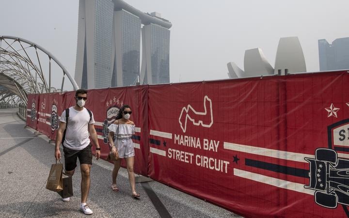 Tourists wear protective masks as they walk near the Formula One Singapore Grand Prix night race track while haze blankets Singapore on September 18, 2019. 