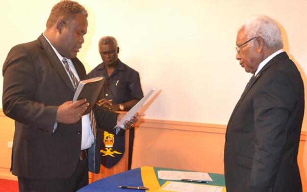 Makario Tagini is sworn in by Governor General David Vunagi as Prime Minister Sogavare looks on.