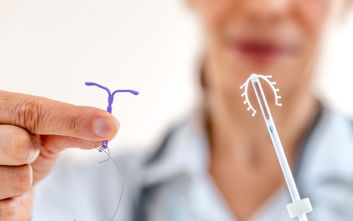 Female doctor holding two kinds of intrauterine device for birth control IUD