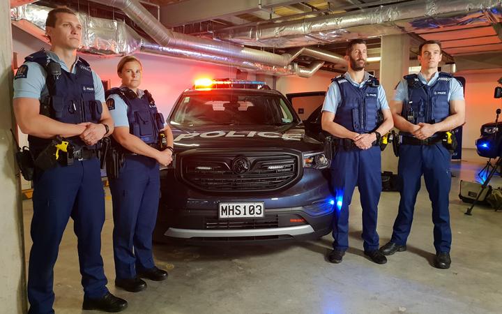 Police officers stand next to the new special patrol vehicle. 