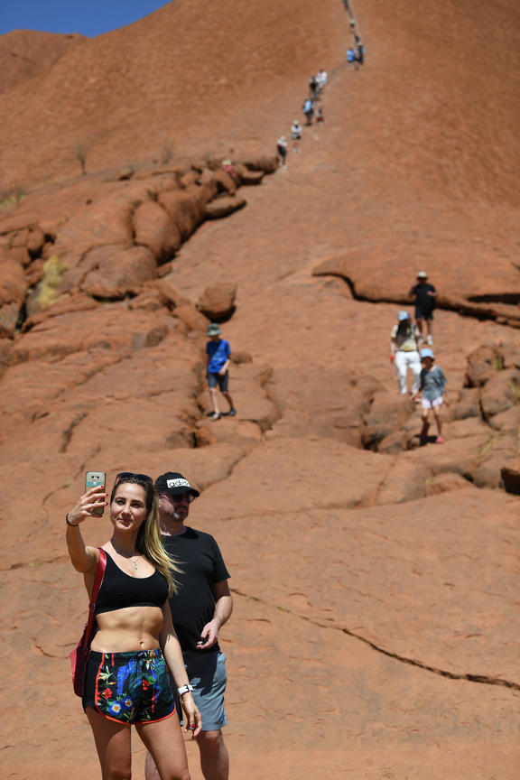 Tourists climb the Uluru, also known as Ayers Rock, on a sunny day at Uluru-Kata Tjuta National Park in Australia's Northern Territory on October 25, 2019. 