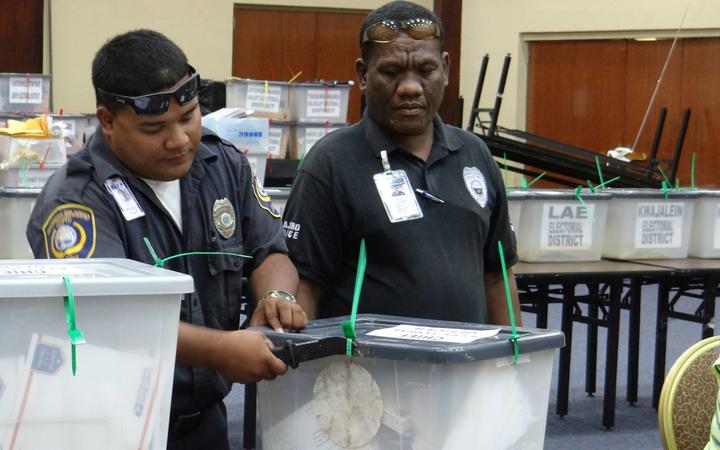 In this file photo from the 2015 election in the Marshall Islands, police officers open a box containing absentee ballots received from Marshall Islanders living in the United States. November's election will be the first since independence to exclude postal votes.