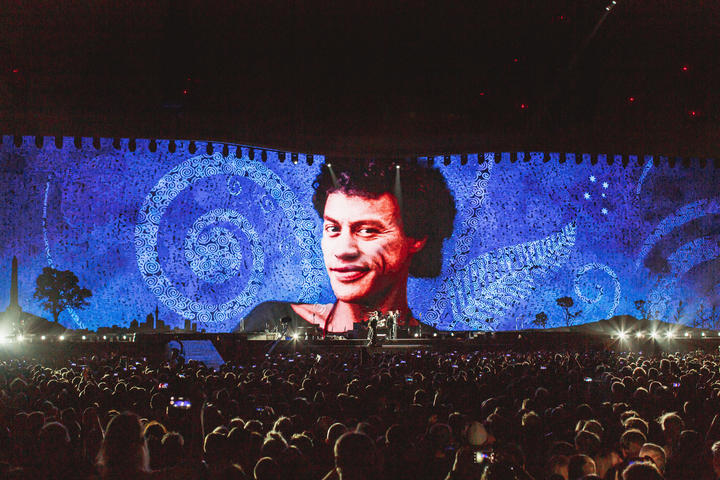 Een beeld van U2's Kiwi roadie Greg Carroll, wordt geprojecteerd tijdens het concert van de band in het Mt Smart Stadium