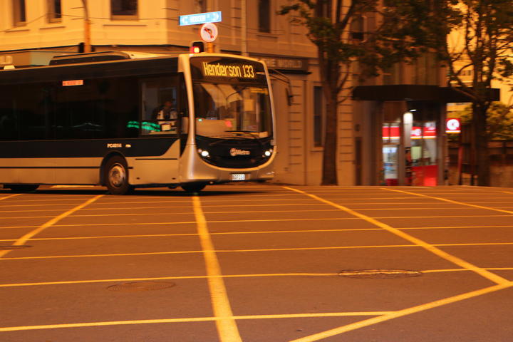 An Auckland bus with its lights on during the day as an orange haze from Australia's bushfires hangs over the city.